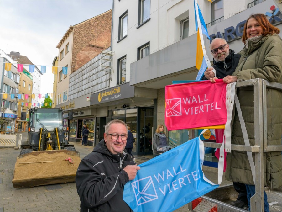 Citymanagerin Gesa Delija hängt mit zwei Mitarbeitern der MCC Werbeservice Wimpelketten im Wallviertel auf - Walter Schernstein